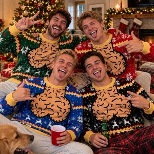 May include: Four long-sleeved knit sweaters featuring a repeating holiday pattern of snowflakes and reindeer, with a large, central, tan-colored graphic of a phallic shape. The sweaters have yellow ribbed collars and cuffs, available in green, red, blue, and black.