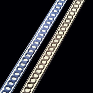 May include: Two strips of decorative trim arranged diagonally. One strip features a blue woven chain-link pattern on a cream background, while the other displays a brown woven chain-link pattern on a cream background, both with dark edges.