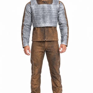 May include: A brown jacket and matching trousers set with a distressed finish, paired with a grey, ribbed, cropped chest plate armor piece. The jacket features long sleeves with grey panels and brown textured detailing, while the trousers are plain brown.