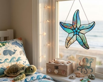 Puede incluir: Un atrapasoles de vitral con forma de estrella de mar en tonos azul, turquesa y blanco, con ilustraciones detalladas de temática oceánica que incluyen olas, corales y conchas. La pieza cuelga de una cadena de metal plateado en una ventana.