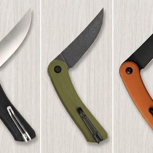 May include: Three folding knives with curved handles and partially open blades. The first has a black handle and silver blade, the second an olive green handle and dark blade, and the third an orange handle with a black blade, each with a pocket clip.