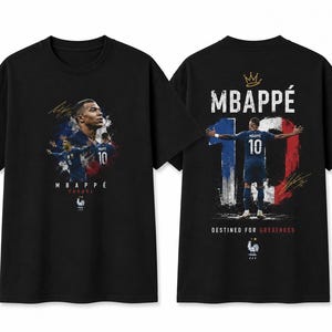 以下が含まれることがあります： キリアン・エムバペのグラフィックがプリントされた黒の半袖Tシャツ。前面には彼のポートレートとアクションショット、「MBAPPÉ FRANCE」の文字が描かれています。背面には背番号「10」、王冠、「DESTINED FOR GREATNESS」の文字と共に後ろ姿が描かれています。