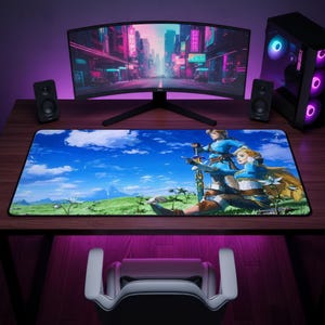 May include: A rectangular desk mat featuring a vibrant, full-color illustration of two fantasy characters in blue tunics standing in a grassy field under a bright blue sky with white clouds. One character holds a glowing sword, while the other stands beside them.