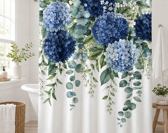 May include: A white shower curtain featuring a botanical print of large blue and light blue hydrangea flower clusters interspersed with green eucalyptus leaves and small white blossoms, hanging from a silver rod in a bathroom setting.