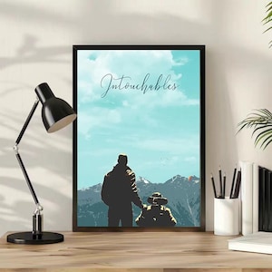 Puede incluir: Una lámina artística enmarcada con una ilustración estilizada de dos figuras, una de pie y otra en silla de ruedas, mirando hacia una cordillera bajo un cielo azul claro. La palabra Intouchables está escrita en cursiva oscura sobre ellos.