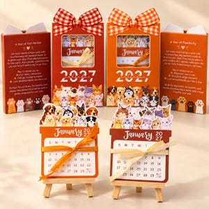 May include: Two 2027 desk calendars featuring cat and dog themes, displayed with matching boxes topped with gingham bows. Each calendar sits on a small wooden easel, showing January 2027 with animal illustrations and ribbon accents.