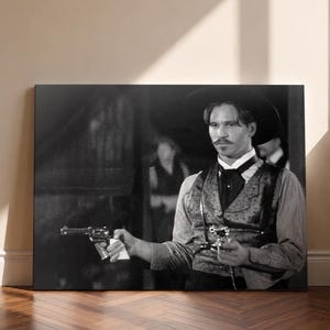 Puede incluir: Un lienzo en blanco y negro que muestra a una persona con un sombrero de ala ancha, un chaleco estampado y una camisa de cuello. La persona sostiene un revólver en cada mano, con una expresión concentrada, en un estilo cinematográfico.