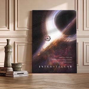Op de afbeelding: Een rechthoekige canvasprint met een ruimte-scène met een zwart gat, een roterend ruimtestation en de tekst: "NEWTON'S THIRD LAW THE ONLY WAY TO MOVE FORWARD, IS TO LEAVE SOMETHING BEHIND." en de titel "INTERSTELLAR" in witte letters.