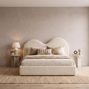 Cama moderna con plataforma de bouclé y cabecero escultural ondulado, tapizada en color crema.