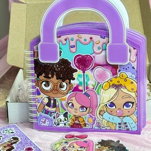 May include: A purple handbag-shaped spiral notebook featuring a colorful cartoon illustration of three characters, a cat, and heart-shaped balloons. The notebook includes a set of matching character stickers and is packaged in a cardboard box.