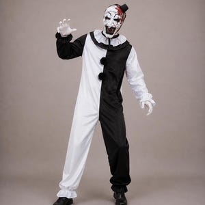 May include: A black and white clown costume featuring a long-sleeved jumpsuit with a split colour design, a ruffled collar, and two black pom-poms. The ensemble includes a matching white mask with black facial features and red blood-like stains.