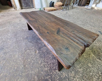 Mesa de centro rústica de madeira maciça com borda natural e acabamento em nogueira escura.
