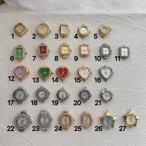 Puede incluir: Una colección de veintisiete esferas de reloj pequeñas en varias formas, incluyendo diseños redondos, cuadrados, de corazón y de estrella. Las esferas presentan tonos dorados y plateados, algunas con cristales, numeradas del uno al veintisiete.