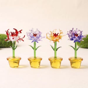 May include: Four miniature glass flower figurines in yellow pots. Each features a green stem, two leaves, and a multi-petaled bloom in red, light purple, yellow-orange, or dark blue. The glass petals have a spiky, irregular shape.