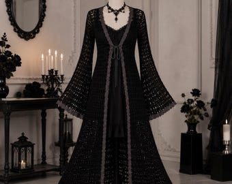 May include: A black crochet duster cardigan featuring long flared sleeves, an open front with a thin tie closure, and a grey scalloped lace trim along the edges. The garment is displayed on a mannequin, layered over a black dress with a lace neckline.