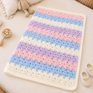 May include: A rectangular crochet blanket featuring horizontal stripes in alternating colors of cream, light blue, soft pink, and lavender. The blanket is crafted with a textured stitch pattern and finished with a solid cream border along all edges.