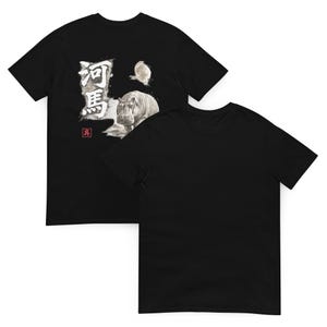 以下が含まれることがあります： 黒の半袖Tシャツ。カバのグラフィックプリント、小さな円形の図形、河馬と書かれた日本語の漢字、そして左側には白い文字が入った小さな赤い四角いスタンプがデザインされています。