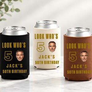 Puede incluir: Tres enfriadores de latas cilíndricos en negro, crema y marrón. Cada uno presenta el texto dorado "LOOK WHO'S 50 JACK'S 50TH BIRTHDAY" y una pequeña fotografía circular del rostro de un hombre junto al número 50.
