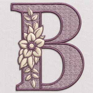 May include: An embroidered letter B featuring a mauve Greek key pattern background and a vertical arrangement of cream-colored floral motifs with leaves. The design is outlined in a dark purple thread, creating a textured and decorative applique.