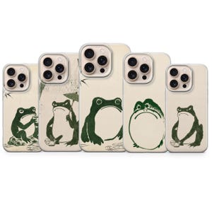 Peut inclure: Cinq coques de smartphone alignées, chacune présentant un fond crème et une illustration unique de grenouille en encre vert foncé. Les grenouilles sont représentées dans diverses postures, tenant une tasse, un parapluie ou un bol.