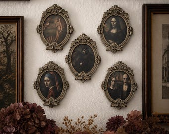 May include: A collection of five oval-shaped wall frames with ornate, metallic gold-toned detailing. Each frame contains a portrait painting featuring dark, moody figures. The frames are arranged in a cluster on a textured, off-white wall surface.
