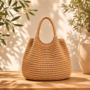 May include: A tan-coloured, hand-crocheted tote bag with a rounded silhouette and a single integrated handle. The bag features a consistent, textured horizontal stitch pattern throughout its body, crafted from a natural-toned, fibrous material.