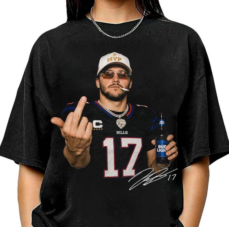 May include: A black t-shirt featuring a graphic of a person wearing a white MVP cap, sunglasses, and a black football jersey with the number 17. The person is holding a Bud Light bottle and giving the middle finger. A white signature is printed below.