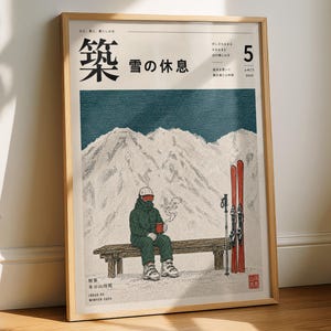 May include: A framed poster featuring a stylized illustration of a person in a dark green ski suit sitting on a wooden bench, holding a red mug. Beside them stand red skis and poles against a backdrop of snow-covered mountains and text.