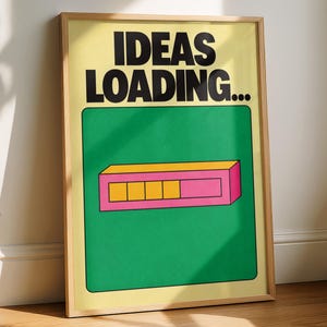 Op de afbeelding: Een ingelijste kunstprint met een lichtgele achtergrond en de dikgedrukte zwarte tekst IDEAS LOADING... boven een groen vierkant met een roze rechthoekige voortgangsbalk met vier gele segmenten en één leeg roze segment.