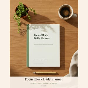 Pode incluir: Um planejador diário Focus Block com capa verde clara e lombada verde escura. A capa apresenta o texto Focus Block Daily Planner, junto com texto menor. Uma caneta dourada, uma xícara de café branca e uma pequena planta verde estão próximas.