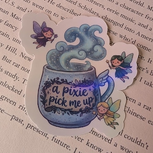 May include: A die-cut sticker featuring a speckled blue mug with wings, emitting swirling blue steam. The mug displays the text 'a pixie pick me up' on a banner. Three small fairies with wings and wands surround the mug, each with a different hair color: purple, black, and blonde.