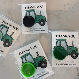 May include: Four party favor cards in clear plastic sleeves, each featuring a green tractor illustration and the text THANK YOU FOR RIDING BY! WALKER'S 4TH BIRTHDAY. Each card includes a circular plastic cap in black, green, or lime green.