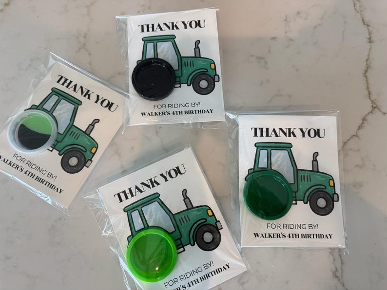 May include: Four party favor cards in clear plastic sleeves, each featuring a green tractor illustration and the text THANK YOU FOR RIDING BY! WALKER'S 4TH BIRTHDAY. Each card includes a circular plastic cap in black, green, or lime green.