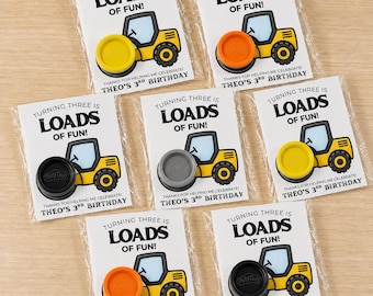 May include: Seven party favor cards in clear plastic sleeves, each featuring a yellow construction vehicle illustration and the text "TURNING THREE IS LOADS OF FUN! THANKS FOR HELPING ME CELEBRATE! THEO'S 3RD BIRTHDAY" with a round Play-Doh container.