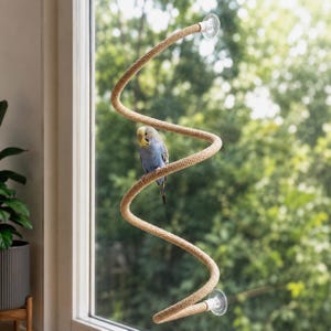 Op de afbeelding: Een lichtblauwe en gele grasparkiet zit op een flexibele, spiraalvormige zitstok van beige touw. De zitstok is aan beide uiteinden met doorzichtige zuignappen aan een raam bevestigd, waardoor een kronkelend pad voor de vogel ontstaat.