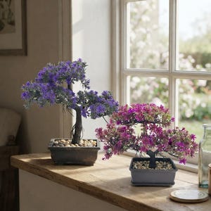 May include: Two artificial bonsai trees in rectangular pots. One tree features vibrant purple foliage with a dark trunk, while the other displays magenta and green leaves with a black trunk. Both pots are filled with small, light-colored decorative stones.