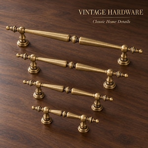 May include: Four antique brass cabinet pulls of varying lengths arranged diagonally. Each handle features a central tapered rod with decorative finials and two mounting posts. The text VINTAGE HARDWARE Classic Home Details is visible.