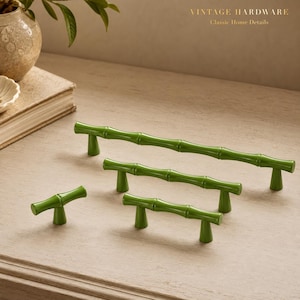 May include: A collection of four green cabinet hardware pieces shaped like bamboo stalks, including one small knob and three handles of varying lengths, each featuring a smooth, glossy finish and two small conical mounting posts for attachment.