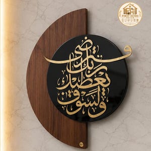 Pode incluir: Uma peça decorativa de parede com uma base semicircular de madeira castanho-escura sobreposta por um painel circular preto. O painel preto apresenta uma intrincada caligrafia árabe dourada. Um pequeno logótipo circular no canto superior direito diz FIRST HOME DECOR.
