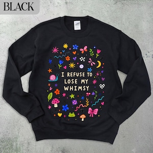 Black sweatshirt with colorful whimsical illustrations and the text "I refuse to lose my whimsy".