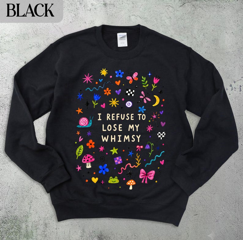 Black sweatshirt with colorful whimsical illustrations and the text "I refuse to lose my whimsy".