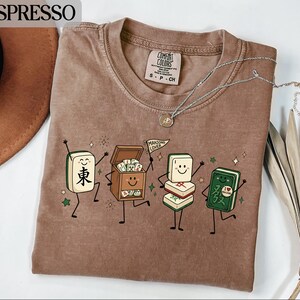 Brown t-shirt with cartoon mahjong tiles celebrating and a "Mahjong Lover" flag.