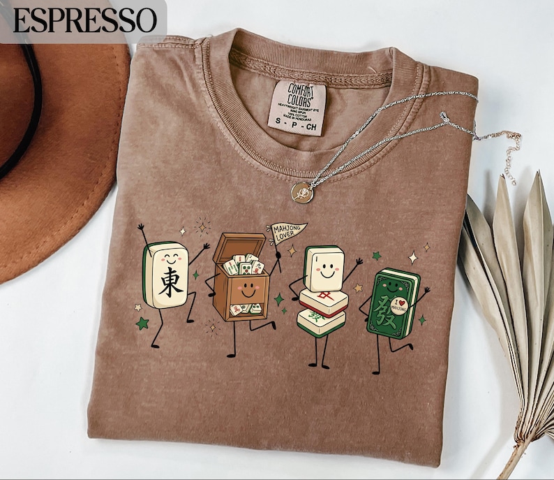 Brown t-shirt with cartoon mahjong tiles celebrating and a "Mahjong Lover" flag.