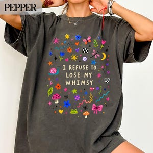 Dark gray t-shirt with colorful whimsical drawings and "I REFUSE TO LOSE MY WHIMSY" text.