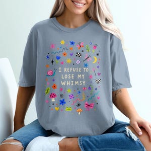 T-shirt with colorful whimsical doodles and text "I REFUSE TO LOSE MY WHIMSY."