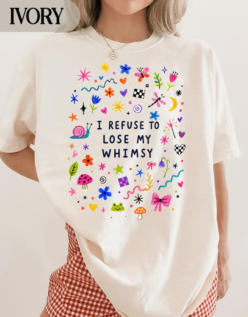 Ivory t-shirt with colorful whimsical drawings and text "I REFUSE TO LOSE MY WHIMSY".