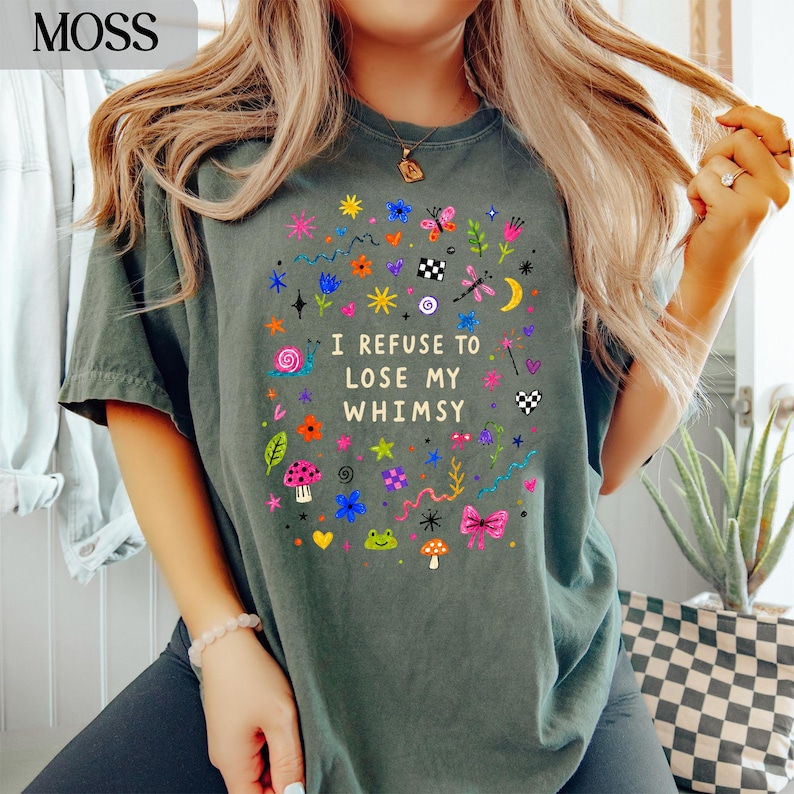 Green t-shirt with colorful whimsical graphics and "I REFUSE TO LOSE MY WHIMSY" text.