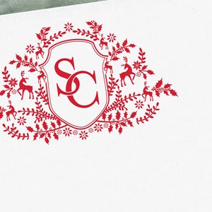 Op de afbeelding: Rood monogram met de letters "SC" in een wit schild omringd door een krans van rode hulstbladeren, bessen en rendieren.