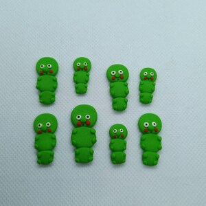 May include: Eight green and red cartoon caterpillar figurines with different facial expressions.