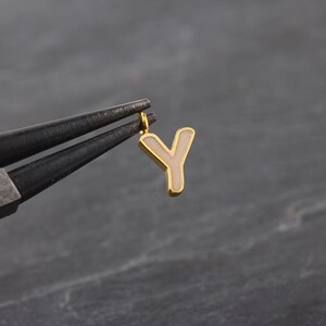 May include: Gold charm with the letter Y in white enamel. The charm has a loop at the top for attaching to a necklace or bracelet.